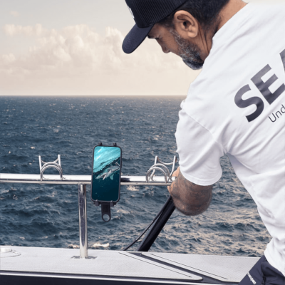 Person on boat using Seavu system to livestream underwater footage from action camera to phone
