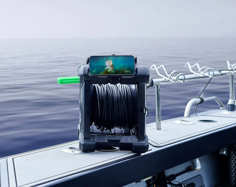 Seavu Explorer cable reel on boat deck with phone displaying live underwater footage of a snapper